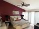 A well-lit bedroom featuring a ceiling fan, a large bed with neutral bedding and a striking red accent wall at 4617 Gonzales Dr, Las Vegas, NV 89130