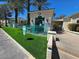Westpark Condos pool entrance with turquoise fencing, vibrant green grass, and mature palm trees at 5155 W Tropicana Ave # 2089, Las Vegas, NV 89103