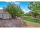 Private backyard features a covered patio, lush lawn, mature trees, and a storage shed for extra space at 5222 Joshua Jose St, North Las Vegas, NV 89031