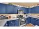 Well-equipped kitchen featuring stainless steel appliances, granite countertops, and charming blue cabinetry at 5222 Joshua Jose St, North Las Vegas, NV 89031