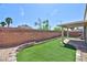 Backyard featuring synthetic grass, brick retaining wall, patio, and covered seating area at 5904 Oakton St, Las Vegas, NV 89130
