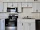 Close up of a kitchen that features modern appliances, stainless steel microwave, white cabinets, and gray countertops at 5928 Willard St, Las Vegas, NV 89122