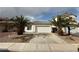 Charming single-story home featuring a two-car garage, desert landscaping, and mature palm trees at 7062 Russell Ranch Ave, Las Vegas, NV 89113