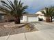 Single-story home featuring a two-car garage, desert landscaping, rock beds, and mature palm trees at 7062 Russell Ranch Ave, Las Vegas, NV 89113