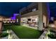 Beautiful backyard at night with a synthetic grass, covered patio, string lights and exterior uplighting at 746 Horizon Canyon Dr, Henderson, NV 89052