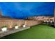 Lush backyard with artificial turf, potted plants, and ambient wall sconces at 746 Horizon Canyon Dr, Henderson, NV 89052