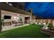 Relaxing backyard featuring an outdoor dining area, lush artificial turf, and decorative planter beds at 746 Horizon Canyon Dr, Henderson, NV 89052