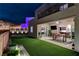 A luxurious backyard featuring desert landscaping, synthetic grass, and a dining area with a covered patio at 746 Horizon Canyon Dr, Henderson, NV 89052