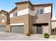 Two-story townhome featuring neutral stucco, attached garage, and gated entrance on a patterned paved driveway at 7476 Opal Star St, North Las Vegas, NV 89084
