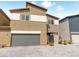 Two-story townhome featuring neutral stucco, attached garage, and gated entrance on a patterned paved driveway at 7476 Opal Star St, North Las Vegas, NV 89084