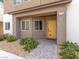 Inviting home exterior with a yellow front door, stone accents, and landscaping, creating a welcoming entrance at 7476 Opal Star St, North Las Vegas, NV 89084