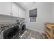Modern laundry room with front load washer and dryer set, wood look tile floors and bright lighting at 845 Loch Katrine Ave, Henderson, NV 89012