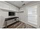 This home office features wood look tile floors, bright lighting, a modern desk and floating storage shelves at 845 Loch Katrine Ave, Henderson, NV 89012