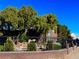 Landscaped front yard featuring mature trees, brick fencing, and secure rod iron at 8690 W Ford Ave, Las Vegas, NV 89148