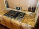 Close-up of a gas cooktop installed in granite countertops and surrounded by wood cabinets at 8690 W Ford Ave, Las Vegas, NV 89148