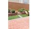 Landscaped backyard featuring well-maintained plants, lawn, brick retaining wall, and an inviting patio space at 10077 Cooper Mountain St, Las Vegas, NV 89141