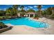 View of a community pool with a covered pavilion and lots of lounge chairs surrounded by palm trees and green vegetation at 10809 Garden Mist Dr # 2050, Las Vegas, NV 89135