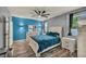 Inviting bedroom featuring wood floors, a fan, and a comfortable bed with bright blue accent wall and bedding at 1152 Pine Cove Ct, Henderson, NV 89011