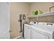 Functional laundry area with washer, dryer, storage shelf, and cleaning supplies at 1152 Pine Cove Ct, Henderson, NV 89011