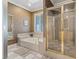 Bright bathroom featuring a soaking tub, glass shower, and neutral tile flooring at 2355 Villandry Ct, Henderson, NV 89074
