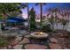 Landscaped backyard with outdoor kitchen, seating area, and stone fire pit at 2355 Villandry Ct, Henderson, NV 89074