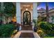 Covered front entrance featuring custom iron door, pillars, and manicured landscaping at 2355 Villandry Ct, Henderson, NV 89074
