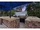 View of a stone outdoor kitchen featuring built in grill, prep areas and sink at 2355 Villandry Ct, Henderson, NV 89074