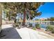 Back patio with comfortable seating shaded by trees, offering beautiful view of the tranquil lake at 2608 Port Of Call Dr, Las Vegas, NV 89128