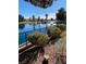 Community lake view with lush landscaping along the shore and clear blue skies in the background at 2608 Port Of Call Dr, Las Vegas, NV 89128