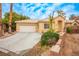 Inviting single-story home featuring a two-car garage, desert landscaping, and curved driveway at 2622 Rimpacific Cir, Las Vegas, NV 89146