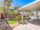Backyard view showing a covered patio, green turf, palm trees, and a playhouse with a slide at 2743 Peekskill Ave, Henderson, NV 89052