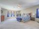 Spacious main bedroom with a ceiling fan, carpet flooring, large windows, and a king-size bed with stylish blue covers at 2743 Peekskill Ave, Henderson, NV 89052