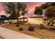 Exterior view of a home at dusk showcasing desert landscaping, a large tree and warm inviting windows at 3597 Cochise Ln, Las Vegas, NV 89169