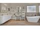 Bright bathroom featuring double vanity, large soaking tub, decorative accents, and privacy glass window at 5892 Castleberry Peak Ave, Las Vegas, NV 89131