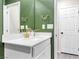 Bathroom featuring green textured wall, white vanity with gold accents, and a bright, clean aesthetic at 6239 Milford Sound St, Las Vegas, NV 89148