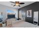 Cozy bedroom features a ceiling fan, dresser with a TV, large windows, and soft, inviting bedding at 6620 Macdoogle St, Las Vegas, NV 89166
