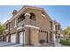 Exterior view of a stucco-style townhome with garages, a balcony, and a Spanish-style roof at 7250 Diamond Canyon Ln # 204, Las Vegas, NV 89149
