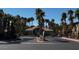 View of the Sunset Cliffs community entrance with palm trees lining the road and buildings in the background at 8985 S Durango Dr # 1010, Las Vegas, NV 89113