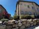 Exterior view of a tan condo building featuring well-maintained landscaping and a sturdy rock wall at 8985 S Durango Dr # 1010, Las Vegas, NV 89113