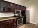 Galley kitchen featuring rich wood cabinetry, stainless appliances, and tiled flooring at 8985 S Durango Dr # 1010, Las Vegas, NV 89113