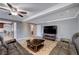 A living room featuring a leather couch, ceiling fan, and a large screen TV on a wooden stand at 902 Dianne Dr, Boulder City, NV 89005