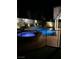 Swimming pool and hot tub at night with decorative stone and illuminated landscaping at 902 Dianne Dr, Boulder City, NV 89005