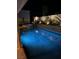 Nighttime view of a sparkling pool with illuminated landscaping and a relaxing hot tub at 902 Dianne Dr, Boulder City, NV 89005