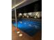 Illuminated inground pool with attached hot tub and stone planters at night at 902 Dianne Dr, Boulder City, NV 89005
