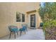 Relaxing patio with two blue chairs, table, greenery, and a door into the home at 9066 Hilverson Ave, Las Vegas, NV 89148