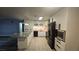 Open kitchen features white cabinets, an island with bar stools, and sleek black appliances at 928 Rockview Dr # 102, Las Vegas, NV 89128
