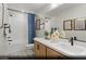 Bright bathroom featuring modern vanity, quartz counters, framed mirror, and shower-tub with blue striped curtain at 9671 S Conquistador St # Lot 18, Las Vegas, NV 89178