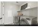 Well-lit laundry room with front load washer and dryer, open shelving, and stylish tile flooring at 9671 S Conquistador St # Lot 18, Las Vegas, NV 89178