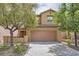Inviting two-story home featuring a tile roof, tan stucco, a two-car garage, and mature trees at 11913 Alava Ave, Las Vegas, NV 89138