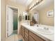 Well-lit bathroom featuring double sinks, tiled countertops, and a shower with a green curtain at 2725 S Nellis Blvd # 2083, Las Vegas, NV 89121
